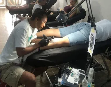 Artist creating a custom tattoo in Bali studio for client on tattoo bed.